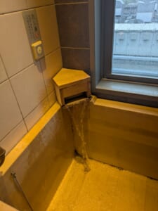 湯口から天然温泉が注がれる客室の檜風呂。壁に「たし湯」ボタン